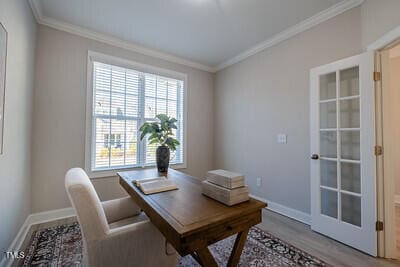 office featuring light wood-style flooring, baseboards, and crown molding