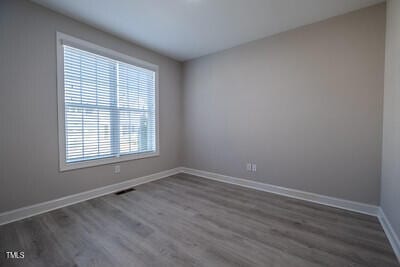 spare room with baseboards and dark wood finished floors