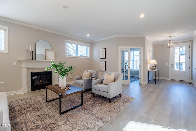 living area with a high end fireplace, a wealth of natural light, crown molding, and light wood-style flooring