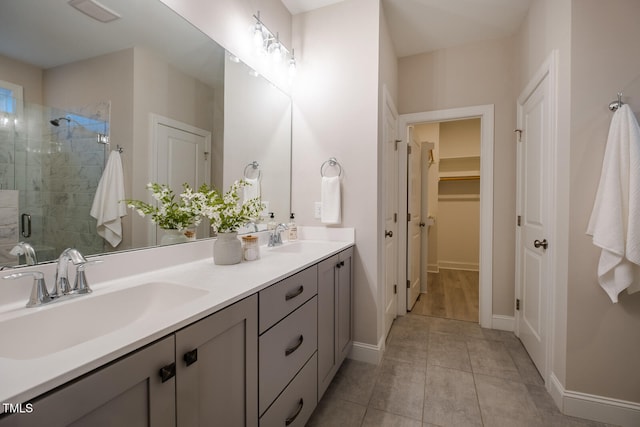 full bath with a sink, double vanity, a stall shower, and a walk in closet