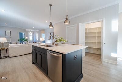 kitchen featuring a sink, open floor plan, light countertops, dishwasher, and an island with sink