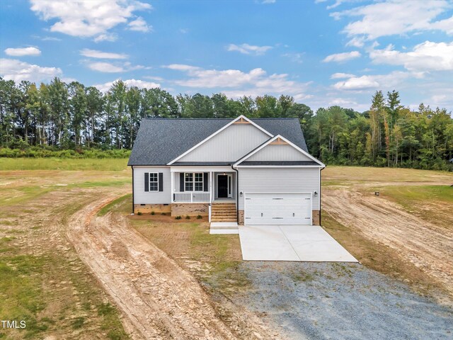 view of front of house featuring a garage, a front lawn, and covered porch