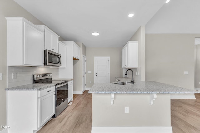 kitchen featuring appliances with stainless steel finishes, kitchen peninsula, white cabinetry, and light hardwood / wood-style flooring