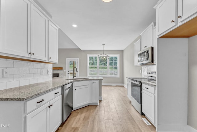 kitchen featuring light stone counters, white cabinets, sink, stainless steel appliances, and light hardwood / wood-style floors