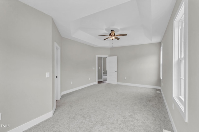 unfurnished room with a tray ceiling, ceiling fan, and light colored carpet