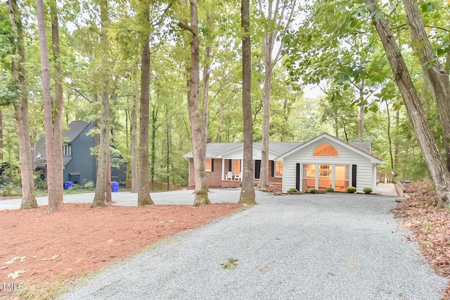 ranch-style house featuring gravel driveway and brick siding