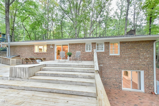 view of front facade with brick siding, a chimney, and a wooden deck