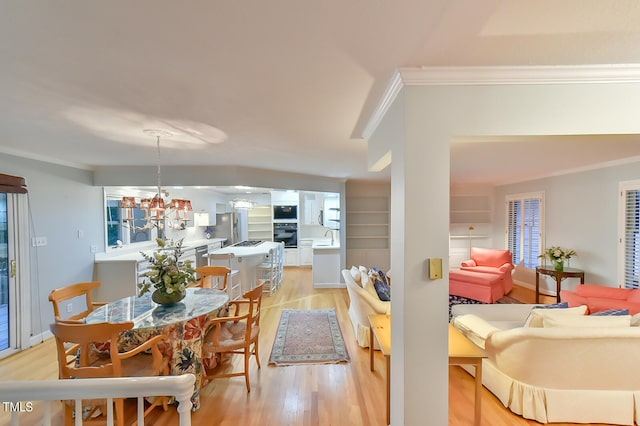 dining area featuring a notable chandelier, light wood-style floors, and crown molding