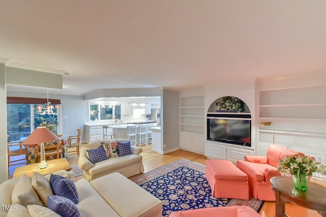 living room with a chandelier, light wood-style floors, and built in shelves