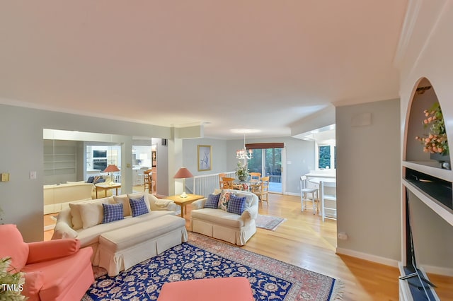 living area with ornamental molding, light wood-style flooring, and baseboards