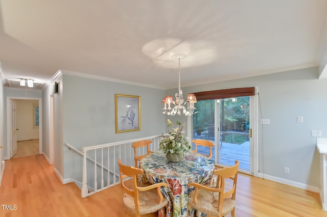 dining room with attic access, ornamental molding, wood finished floors, a chandelier, and baseboards