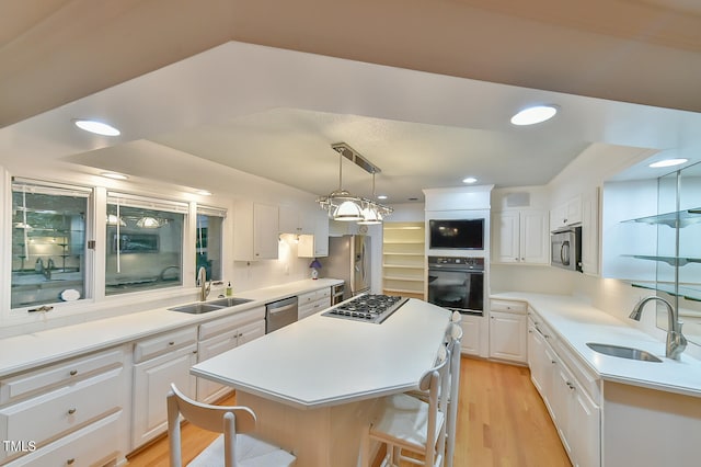 kitchen with light countertops, appliances with stainless steel finishes, a sink, and white cabinets