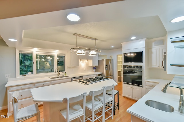 kitchen featuring white cabinets, appliances with stainless steel finishes, light countertops, pendant lighting, and a sink