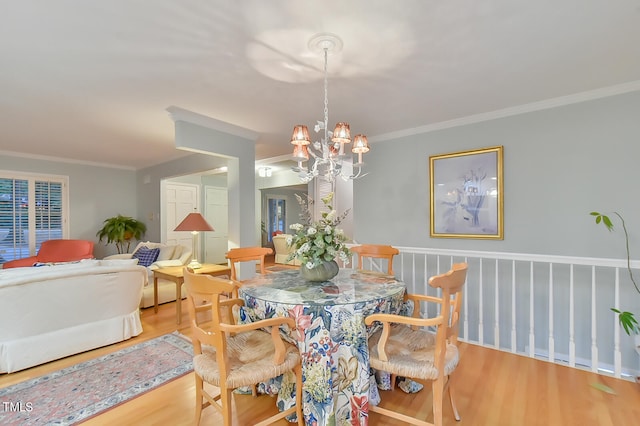 dining space featuring a chandelier, light wood-style flooring, and crown molding