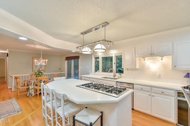 kitchen featuring white cabinets, pendant lighting, light countertops, and a sink