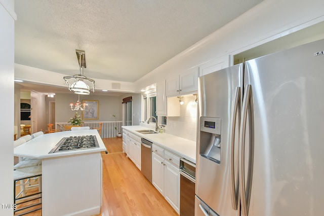 kitchen featuring white cabinetry, a kitchen island, appliances with stainless steel finishes, and light countertops