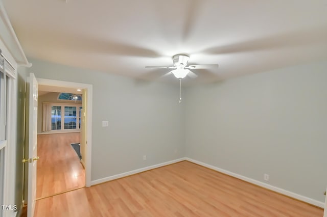 empty room with ceiling fan, wood finished floors, and baseboards