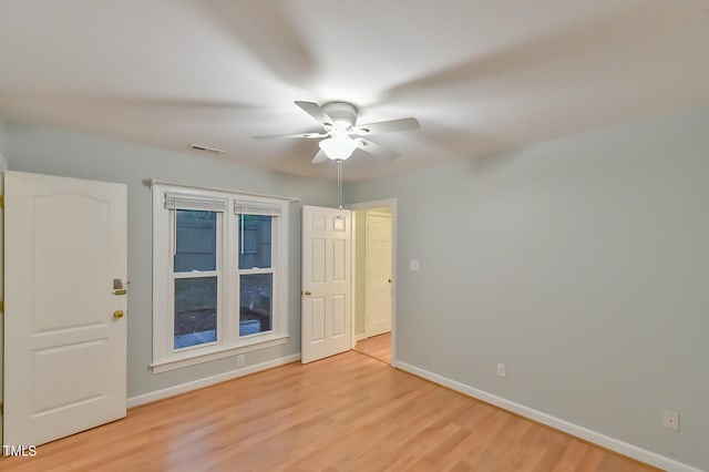 spare room featuring light wood-type flooring, visible vents, baseboards, and a ceiling fan