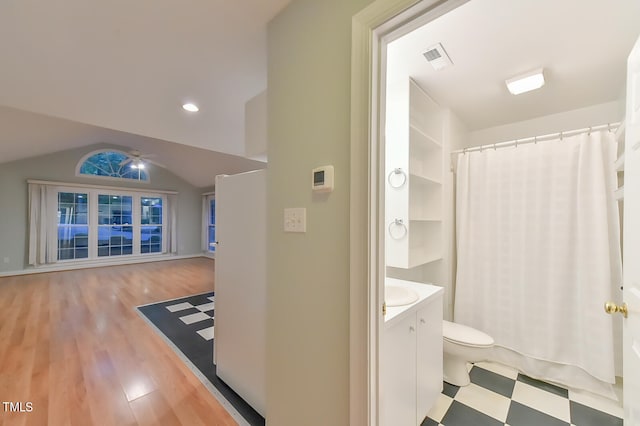 bathroom with visible vents, toilet, wood finished floors, vaulted ceiling, and vanity