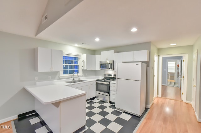 kitchen featuring dark floors, light countertops, appliances with stainless steel finishes, white cabinets, and a sink