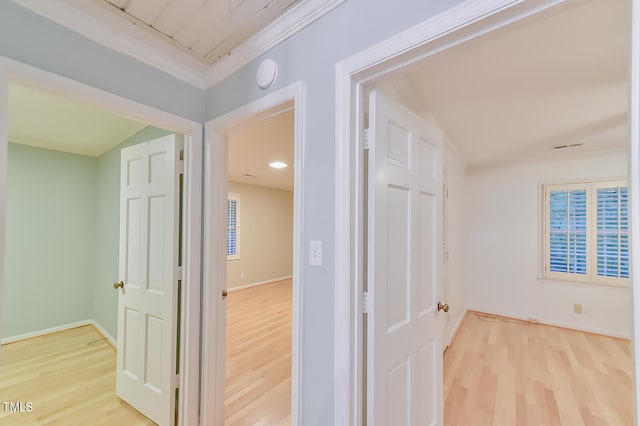 hallway with baseboards, wood finished floors, and ornamental molding