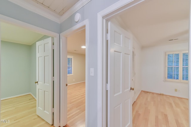 hall featuring light wood-style floors, baseboards, and ornamental molding