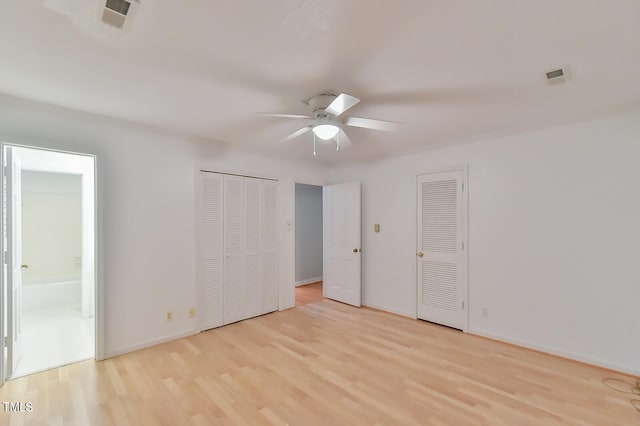 unfurnished bedroom featuring light wood finished floors, multiple closets, visible vents, ensuite bathroom, and baseboards