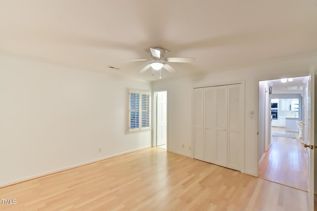 unfurnished bedroom with a ceiling fan, visible vents, baseboards, a closet, and light wood finished floors