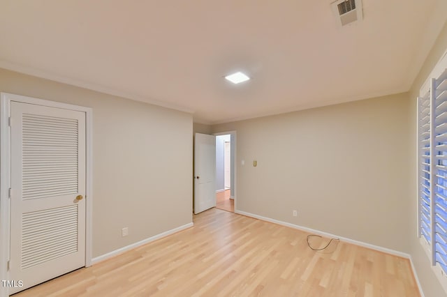 unfurnished bedroom featuring crown molding, light wood-type flooring, visible vents, and baseboards