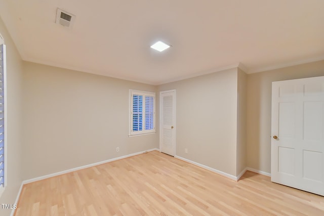 empty room featuring light wood-style flooring, visible vents, and baseboards