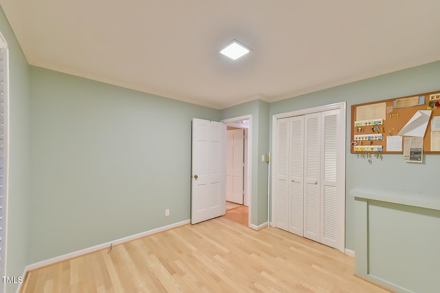 unfurnished bedroom with light wood-style floors, a closet, and baseboards