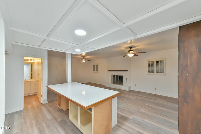 kitchen featuring coffered ceiling, light wood-style flooring, a kitchen island, and open floor plan