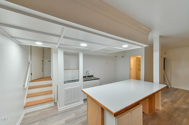 kitchen featuring light wood-type flooring, visible vents, a sink, and a center island