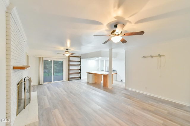 unfurnished living room featuring a ceiling fan, baseboards, a fireplace, and light wood finished floors