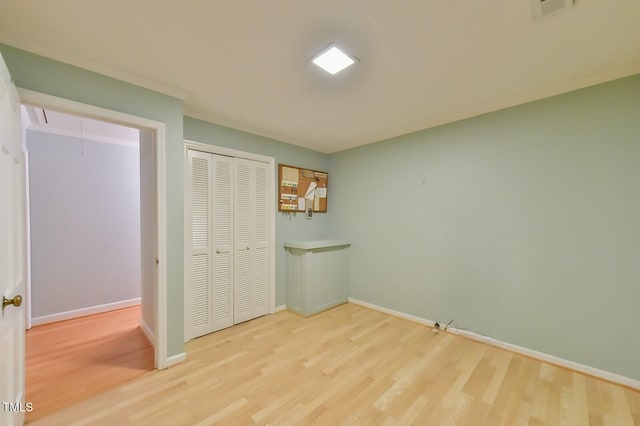 unfurnished bedroom featuring a closet, wood finished floors, attic access, and baseboards