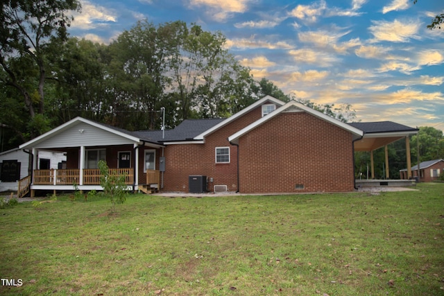 back house at dusk featuring a lawn and central air condition unit