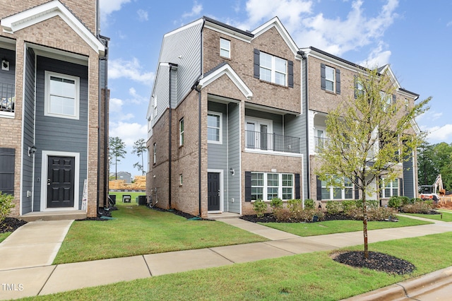 townhome / multi-family property featuring a balcony and a front yard