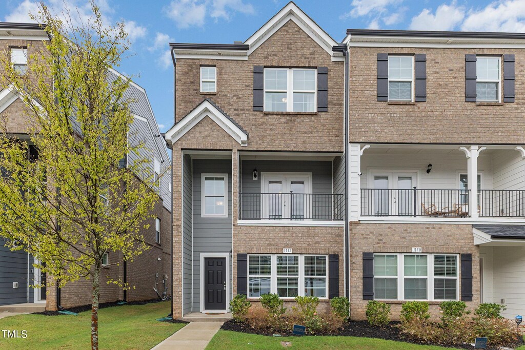 multi unit property featuring a balcony and a front yard