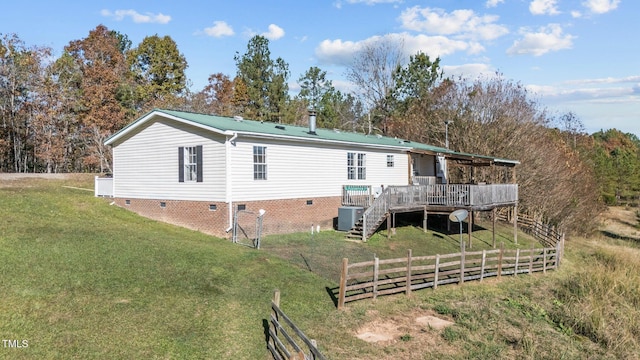 rear view of property with a lawn, a deck, and central air condition unit
