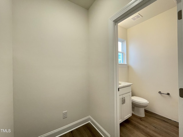 bathroom with toilet, wood finished floors, vanity, visible vents, and baseboards