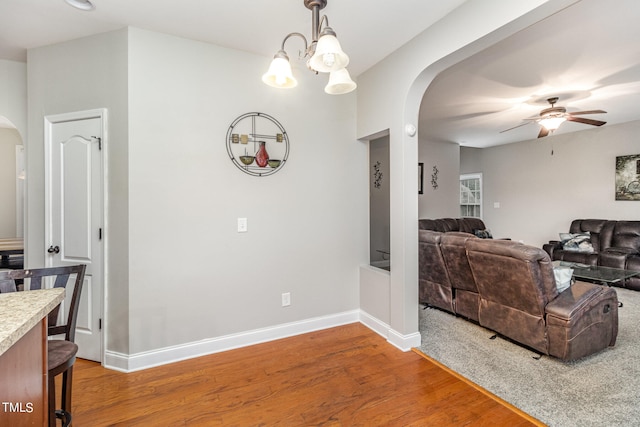 living room featuring ceiling fan with notable chandelier and hardwood / wood-style flooring