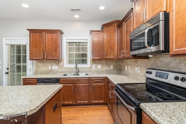 kitchen with light hardwood / wood-style flooring, appliances with stainless steel finishes, tasteful backsplash, and sink