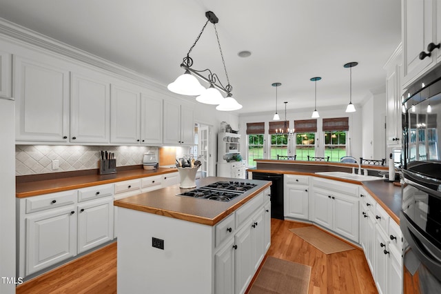 kitchen with black appliances, kitchen peninsula, pendant lighting, and white cabinets