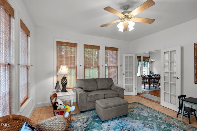 tiled living room featuring french doors and ceiling fan with notable chandelier