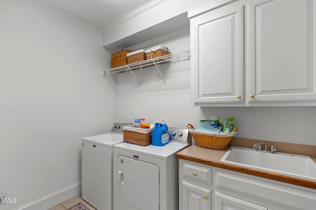 laundry room featuring cabinets, light tile patterned flooring, sink, crown molding, and washer and clothes dryer