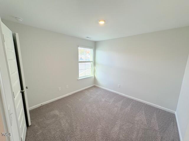 spare room with dark colored carpet