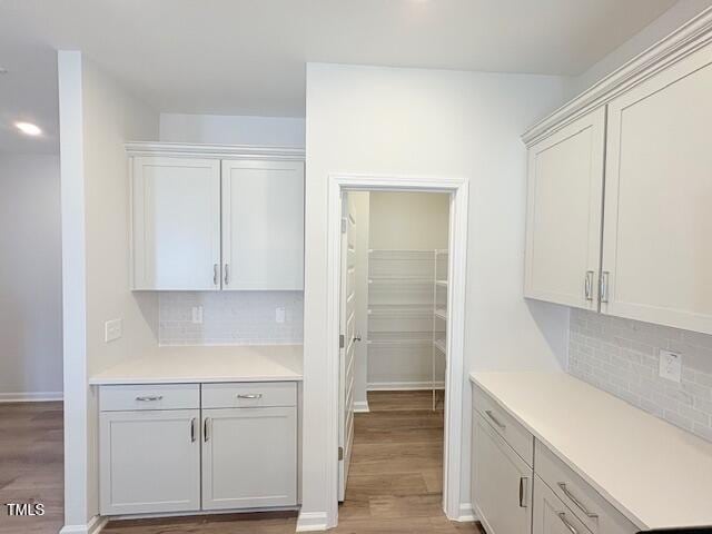 kitchen featuring white cabinetry, decorative backsplash, and wood-type flooring