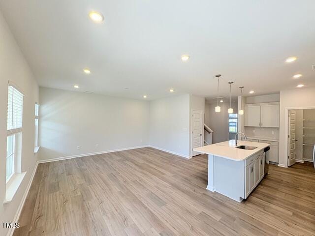 kitchen with a healthy amount of sunlight, sink, light wood-type flooring, and a center island with sink