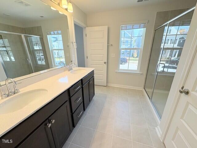 bathroom featuring vanity, a shower with shower door, and tile patterned flooring