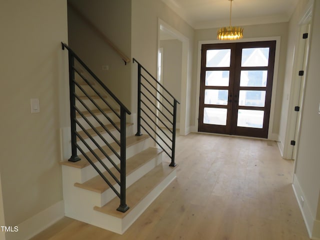 foyer with french doors, ornamental molding, and light hardwood / wood-style flooring